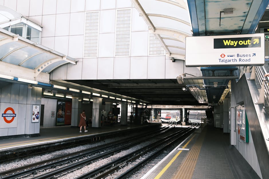 View of Ickenham station platform with a modern train parked alongside, partially visible on the right side of the image. The platform is covered by a curved, transparent canopy supported by white met
